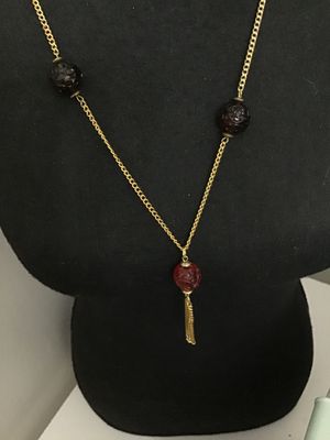Sale Photo Thumbnail #148: Vintage gold-tone chain necklace featuring carved translucent red glass beads and a small metal chain tassel pendant. Has a hook and eye/ring clasp. In good vintage condition with minor surface wear consistent with age.
