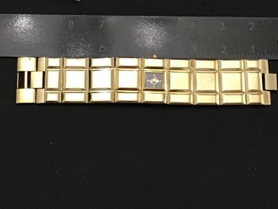Sale Photo Thumbnail #163: A vintage gold-tone fashion watch featuring a wide, geometric segmented link band and a small square dark dial with stylized graphic logo and minimalist hour markers. Measures Workingapproximately 7.5 to 8 inches in total length. Stainless steel or metal 