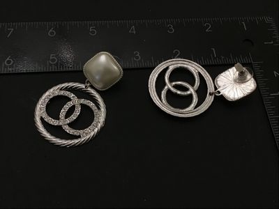 Sale Photo Thumbnail #168: Pair of statement dangle earrings in the style of a designer double-C logo. Features top square faux pearls set in textured silver-tone frames with dangling rope-textured hoops containing rhinestone-set interlocking circles. Silver-tone post backs. Measur
