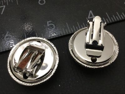 Sale Photo Thumbnail #172: Pair of vintage silver-tone clip-on earrings featuring a textured dome center and chevron patterned outer rim. Each clip-on earring measures approximately 1 inch in diameter. In good condition with functional clip backs and light vintage wear.