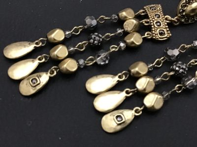 Sale Photo Thumbnail #187: Pair of ornate gold-tone dangle earrings featuring multi-strand drop chains with faceted dark crystal beads and hammered teardrop charms. Pierced post backings. Measure approximately 2.5 to 3 inches long. Good condition with no missing beads or visible da