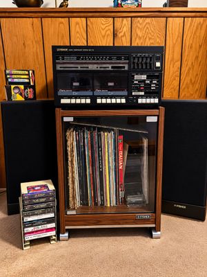 Sale Photo Thumbnail #98: Vintage Fisher MC-713 audio component stereo system with dual cassette deck, matching speakers, wood grain rolling cabinet filled with vinyl records, and cassette tape racks.