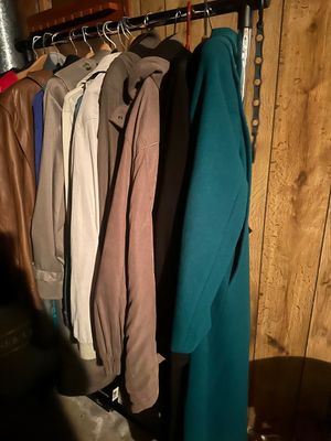 Sale Photo Thumbnail #251: Clothing rack filled with a variety of vintage men's and women's coats and jackets, including leather outerwear, trenches, and a long teal wool coat.