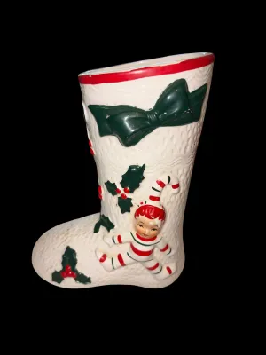 Sale Photo Thumbnail #128: Charming vintage UCAGCO (United China & Glass Company) ceramic Christmas boot planter featuring a whimsical pixie elf dressed in a candy cane-striped outfit, accented with raised holly leaves, berries, and a large green bow. This classic mid-century holid