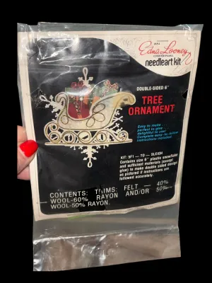 Sale Photo Thumbnail #95: Vintage Edna Looney Original Needle Art Kit featuring a double-sided 6-inch sleigh tree ornament. Kit appears unused and includes felt, sequins, beads, trims, plastic snowflakes, and instructions in the original packaging. Glue not included (as originally