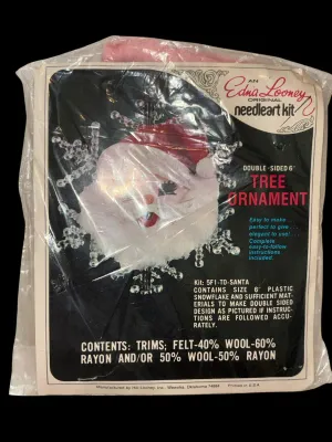 Sale Photo Thumbnail #85: Vintage Edna Looney Original Needle Art Kit featuring a double-sided 6-inch Santa tree ornament. Kit appears unused and includes felt, sequins, beads, trims, plastic snowflake, and instructions in the original packaging. Packaging shows light wear from ag