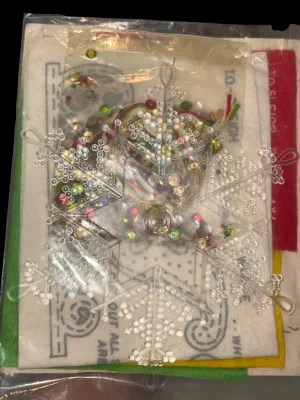 Sale Photo Thumbnail #96: Vintage Edna Looney Original Needle Art Kit featuring a double-sided 6-inch sleigh tree ornament. Kit appears unused and includes felt, sequins, beads, trims, plastic snowflakes, and instructions in the original packaging. Glue not included (as originally