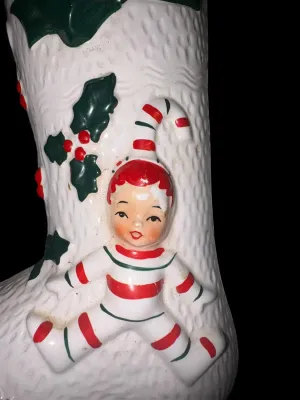 Sale Photo Thumbnail #134: Charming vintage UCAGCO (United China & Glass Company) ceramic Christmas boot planter featuring a whimsical pixie elf dressed in a candy cane-striped outfit, accented with raised holly leaves, berries, and a large green bow. This classic mid-century holid