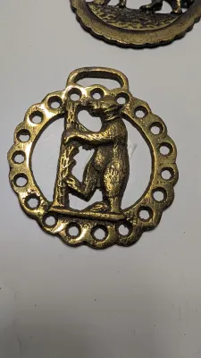 Sale Photo Thumbnail #297: Horse brass bridal medallions (or "horse brasses") are decorative, solid-brass plaques originally used to embellish the bridles and harnesses of working and parade horses. Originating in England in the mid-19th century, carters and farmers first used them