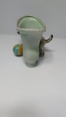 Sale Photo Thumbnail #356: The "UCAGCO China Handpainted Japan Cat, Boot, and Ball" is a charming mid-century vintage figurine. Made in Japan by the United China and Glass Company, it usually depicts a small, hand-painted ceramic kitten (often a tabby) either sitting on a boot/shoe