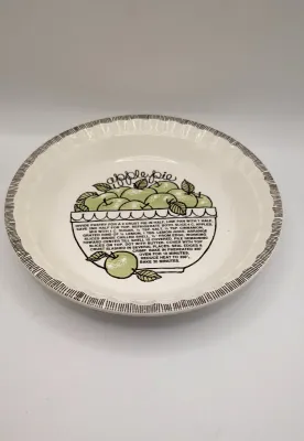 Sale Photo Thumbnail #147: The vintage 1982 Royal China by Jeannette 11" Apple Pie Recipe Plate is a highly collectible, oven-to-table ceramic dish. Featuring a fluted edge and a distinct green and brown apple motif, it lists the exact ingredient amounts and baking instructions dir