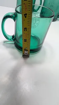 Sale Photo Thumbnail #290: This authentic vintage 1990s Starbucks mug is made in the USA from emerald-tinted, clear glass featuring an etched or embossed classic Siren logo