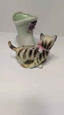 Sale Photo Thumbnail #355: The "UCAGCO China Handpainted Japan Cat, Boot, and Ball" is a charming mid-century vintage figurine. Made in Japan by the United China and Glass Company, it usually depicts a small, hand-painted ceramic kitten (often a tabby) either sitting on a boot/shoe