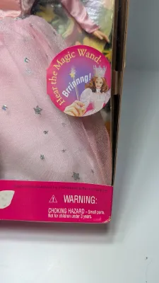 Sale Photo Thumbnail #362: A highly popular playline doll. When you raise her arm, she plays a "brrinnng" magic wand sound effect or says, "Tap your heels together three times". She features strawberry-blonde hair and a pink satin gown with star and butterfly accents