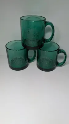 Sale Photo Thumbnail #287: This authentic vintage 1990s Starbucks mug is made in the USA from emerald-tinted, clear glass featuring an etched or embossed classic Siren logo