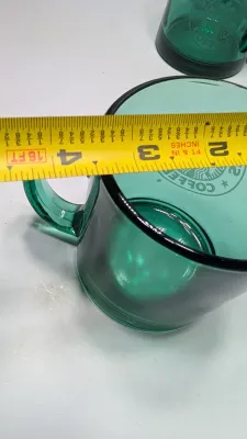 Sale Photo Thumbnail #289: This authentic vintage 1990s Starbucks mug is made in the USA from emerald-tinted, clear glass featuring an etched or embossed classic Siren logo