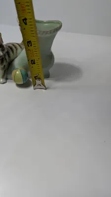 Sale Photo Thumbnail #359: The "UCAGCO China Handpainted Japan Cat, Boot, and Ball" is a charming mid-century vintage figurine. Made in Japan by the United China and Glass Company, it usually depicts a small, hand-painted ceramic kitten (often a tabby) either sitting on a boot/shoe