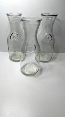 Sale Photo Thumbnail #224: Vintage Paul Masson "Since 1852" 1-liter glass carafes are highly collectible pieces originally manufactured by the Paul Masson Vineyards company to sell wine. Due to their distinct, heavy clear glass and wide-rim silhouette, they are frequently repurpose