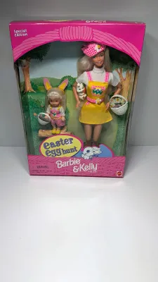 Sale Photo Thumbnail #365: Barbie Doll: Wears a vibrant yellow jumper with an Easter egg pattern pocket, a white t-shirt, a matching pink plaid hat, and shoes.Kelly Doll: Dressed in matching pink plaid overalls, a white t-shirt, and adorable bunny ears.Accessories Included: The set