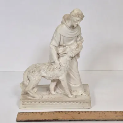 LOT 51: White Devotional Statue of Saint Francis of Assisi Taming the Wolf of Gubbio and Replica Figurine of Michelangelo's Pietà,...
