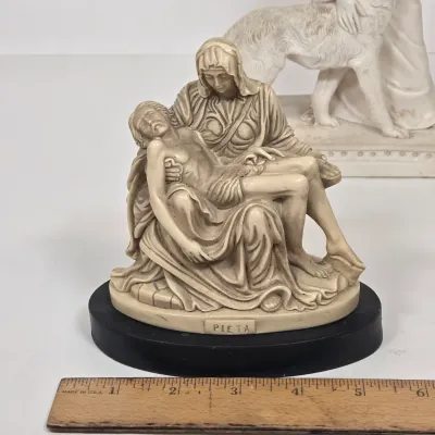 LOT 51: White Devotional Statue of Saint Francis of Assisi Taming the Wolf of Gubbio and Replica Figurine of Michelangelo's Pietà,...