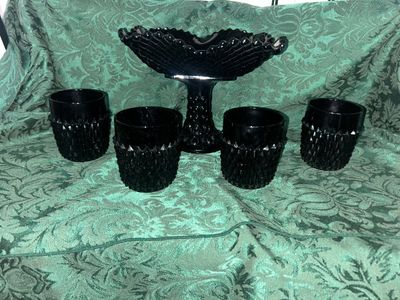 Sale Photo Thumbnail #627: VINTAGE BLACK AMETHYST GLASS COMPOTE PEDESTAL BOWL WITH FOUR MATCHING HOBNAIL/DIAMOND POINT TUMBLERS. FEATURES A TEXTURED GEOMETRIC PATTERN AND STARBURST BASE DETAILS. LIGHT WEAR FROM USE, NO VISIBLE CHIPS OR CRACKS.