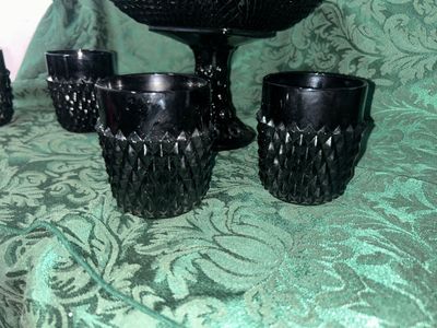 Sale Photo Thumbnail #628: VINTAGE BLACK AMETHYST GLASS COMPOTE PEDESTAL BOWL WITH FOUR MATCHING HOBNAIL/DIAMOND POINT TUMBLERS. FEATURES A TEXTURED GEOMETRIC PATTERN AND STARBURST BASE DETAILS. LIGHT WEAR FROM USE, NO VISIBLE CHIPS OR CRACKS.
