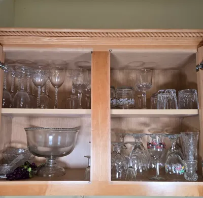 LOT 101: Kitchen Cabinet Lot Including Wine Glasses, Trifle Bowl, and More