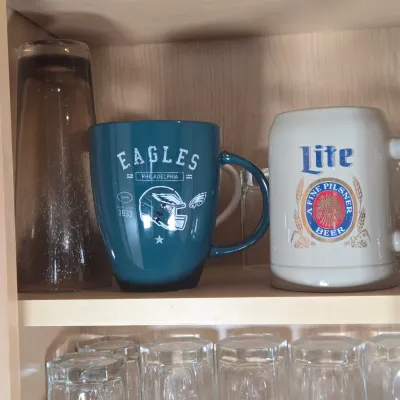 LOT 102: Kitchen Cabinet Lot Including Drinking Glasses. Philadelphia Eagles Mug, Miller Lite Mug, and More