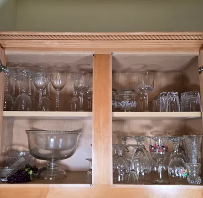 LOT 101: Kitchen Cabinet Lot Including Wine Glasses, Trifle Bowl, and More