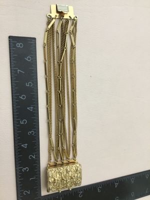 Vintage multi strand, gold tone bracelet, featuring intricate open work, rectangular, sliding centerpiece, class decorated with raised...