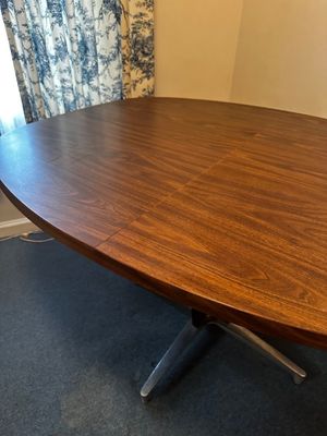 Sale Photo Thumbnail #35: Features a rich walnut-grain laminate veneer surface. It is built with an integrated expansion leaf seam designed to split open for extra seating.Pedestal Base: Supported by a distinctive four-prong cast aluminum and polished chrome "starburst" pedestal b