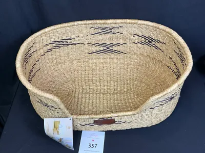 Woven, natural fiber pet bed basket filled with pet care supplies and grooming tools