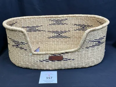 Woven, natural fiber pet bed basket filled with pet care supplies and grooming tools