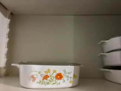 Vintage CorningWare casserole dish featuring the Country Cornflower or Wildflower pattern, complete with a glass lid, sitting alongside...