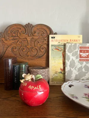 Vintage ceramic apple-shaped trinket box with a small mouse figurine on top, displayed alongside vintage books including "The...
