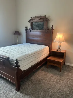Antique Eastlake-style carved wooden bed frame with an ornate headboard and matching footboard.