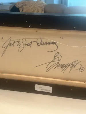 The reverse side of a framed canvas painting, featuring the handwritten title "Just to Start Dreaming" and an artist's...