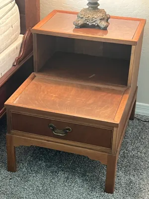 Mid-century modern two-tier step table with a single drawer, brass pull, and open storage cubby.