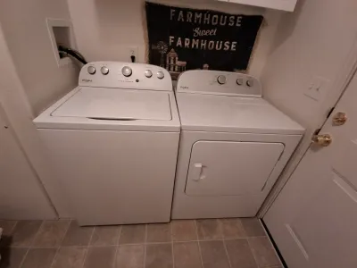Whirlpool top-load washing machine and matching front-load dryer in white, showing light use.