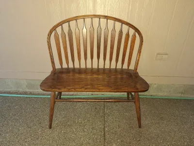 Vintage Windsor-style oak bench featuring a high, arched spindle back with arrow-shaped slats and splayed legs.
