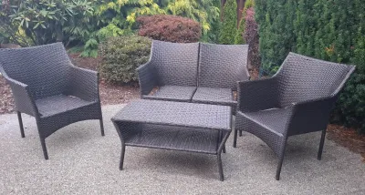 Four-piece dark brown resin wicker patio conversation set, including a loveseat, two armchairs, and a two-tier coffee table.
