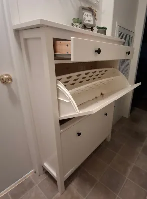 White wooden shoe cabinet featuring a top drawer and two pull-down compartments with black knobs.