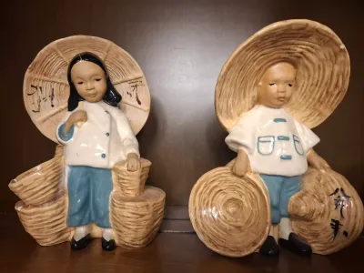 Pair of vintage mid-century ceramic figurines depicting a boy and girl in traditional Asian attire with woven baskets and hats.