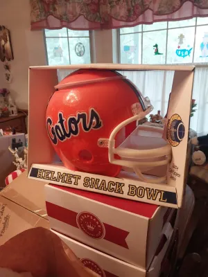 Vintage Florida Gators helmet snack bowl, new in its original packaging, sitting atop stacked Hallmark Keepsake Ornament boxes.