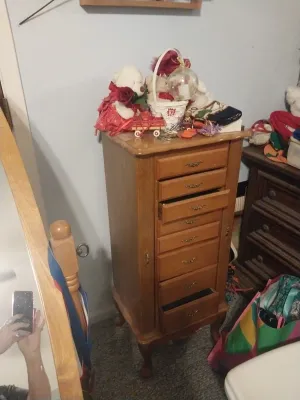 Vintage oak standing jewelry armoire with multiple drawers, side cabinet doors, and cabriole legs, topped with various holiday decorations.