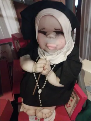 Vintage soft sculpture nun doll, featuring a fabric face with expressive features, dressed in a black habit and white wimple while...