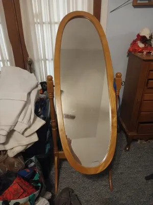 Vintage oval cheval floor mirror in a light oak frame and stand with turned posts.