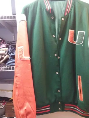 Vintage University of Miami Hurricanes varsity jacket featuring a green wool body, orange leather sleeves, and a chenille 'U'...