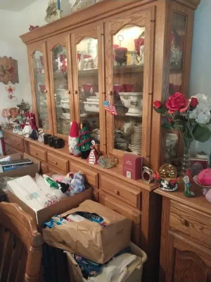 Large oak china hutch with glass-front upper cabinets, interior lighting, and lower storage drawers, filled with various dishware and...